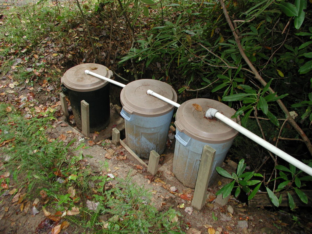 three trash cans with pvc pipes on lids